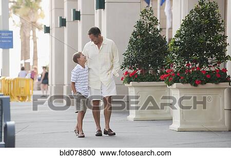 Stock Image - Caucasian father and son walking together. Fotosearch