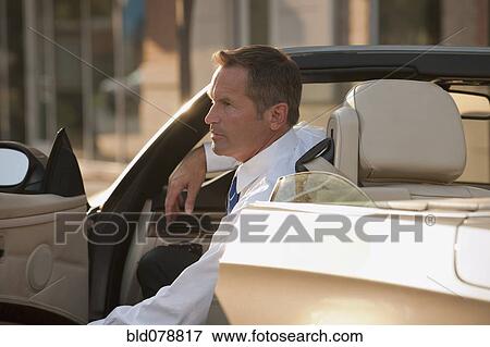Caucasian man getting out of convertible View Large Photo Image Stock Photo - Caucasian man getting out of convertible. Fotosearch
