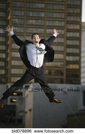 Stock Photograph - Excited mixed race businessman jumping in mid-air. Fotosearch