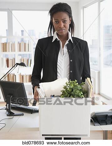 Stock Image - Fired mixed race businesswoman packing belongings. Fotosearch