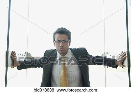 Frowning Hispanic businessman opening doors View Large Photo Image Stock Photo - Frowning Hispanic businessman opening doors. Fotosearch