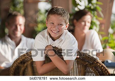 Stock Image - Grinning Caucasian boy in restaurant with family. Fotosearch
