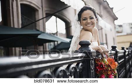 Stock Image - Hispanic bride on balcony smiling. Fotosearch