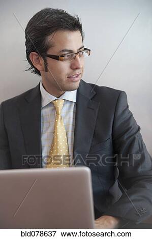 Stock Photo - Hispanic businessman typing on laptop. Fotosearch