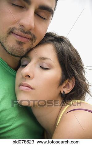 Stock Image - Hispanic couple hugging with eyes closed. Fotosearch