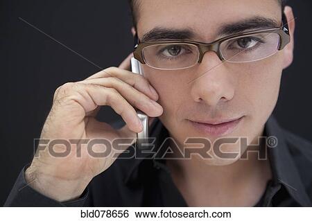 Stock Photograph - Hispanic man in eyeglasses talking on cell phone. Fotosearch