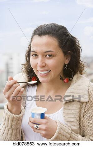 Stock Image - Hispanic woman eating yogurt. Fotosearch