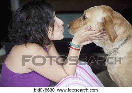 Stock Image - Hispanic woman kissing her dog. Fotosearch