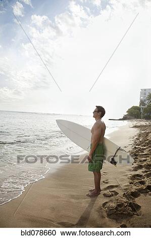 Japanese man holding surfboard on beach View Large Photo Image Stock Image - Japanese man holding surfboard on beach. Fotosearch