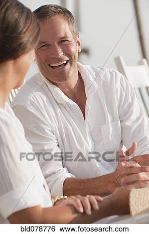 Stock Photograph - Laughing Caucasian husband talking to wife. Fotosearch