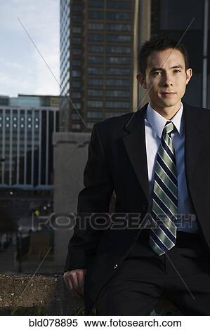 Stock Photography - Mixed race businessman sitting on urban rooftop. Fotosearch