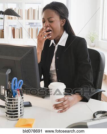 Mixed race businesswoman yawning at desk View Large Photo Image Stock Image - Mixed race businesswoman yawning at desk. Fotosearch