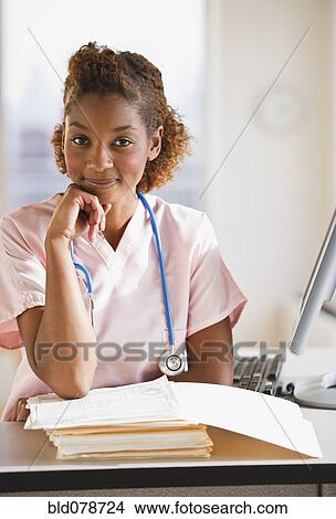 Picture - Mixed race nurse working on medical charts. Fotosearch