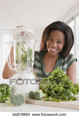 Picture - Mixed race woman blending vegetables. Fotosearch