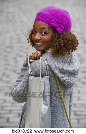 Stock Image - Mixed race woman carrying Christmas gifts. Fotosearch
