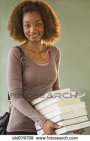 Stock Photo - Mixed race woman carrying stack of books. Fotosearch