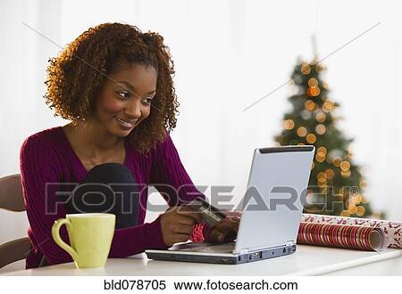 Stock Photography - Mixed race woman Christmas shopping on internet with credit card. Fotosearch