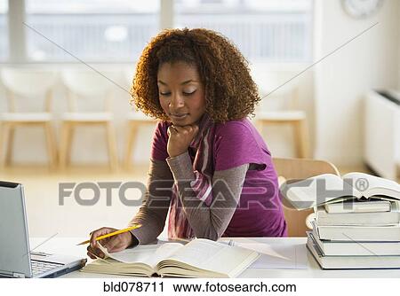 Stock Image - Mixed race woman doing homework. Fotosearch