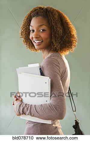 Stock Image - Mixed race woman holding books. Fotosearch