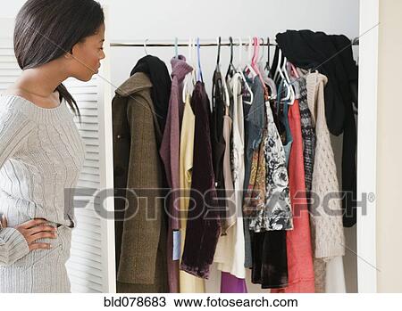 Mixed race woman looking at clothes in closet View Large Photo Image Stock Image - Mixed race woman looking at clothes in closet. Fotosearch