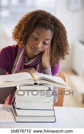 Mixed race woman looking at stack of books View Large Photo Image Stock Image - Mixed race woman looking at stack of books. Fotosearch