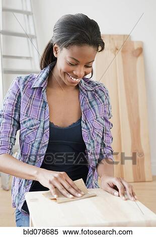 Stock Photography - Mixed race woman sanding wood. Fotosearch
