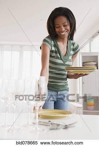 Stock Photography - Mixed race woman setting table. Fotosearch