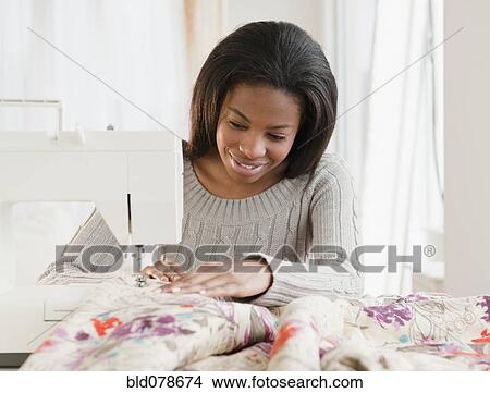 Picture - Mixed race woman sewing with sewing machine. Fotosearch