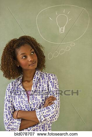 Mixed race woman standing next to thought bubble on blackboard View Large Photo Image Stock Photo - Mixed race woman standing next to thought bubble on blackboard. Fotosearch