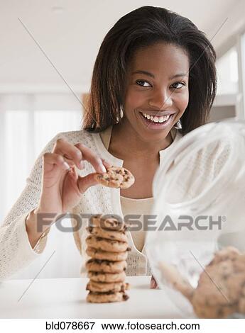 Stock Photo - Mixed race woman taking cookie. Fotosearch