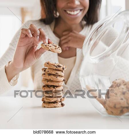 Stock Photo - Mixed race woman taking cookie. Fotosearch