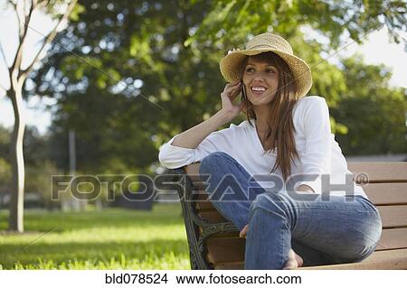 Picture - Mixed race woman talking on cell phone outdoors. Fotosearch