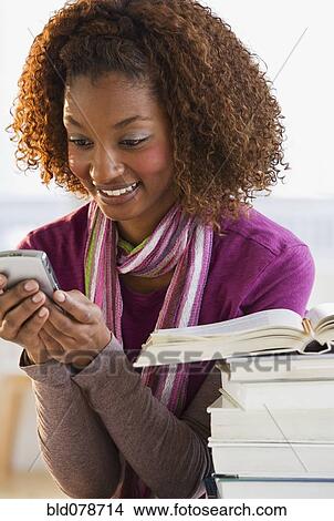 Picture - Mixed race woman text messaging on cell phone. Fotosearch