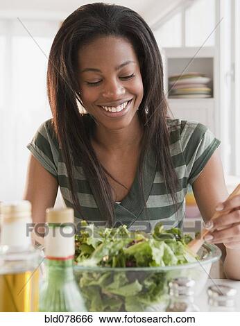 Stock Photograph - Mixed race woman tossing salad. Fotosearch