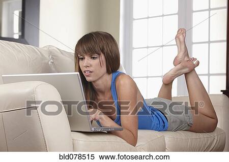 Stock Photography - Mixed race woman using laptop on sofa. Fotosearch