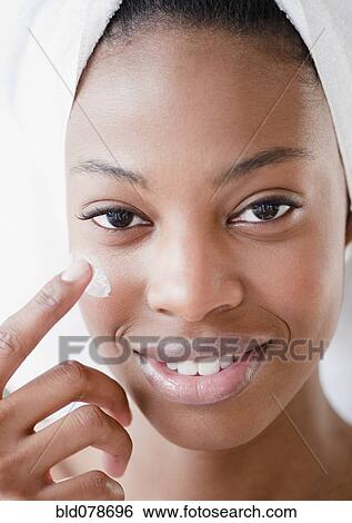 Stock Photograph - Mixed race woman using moisturizer. Fotosearch