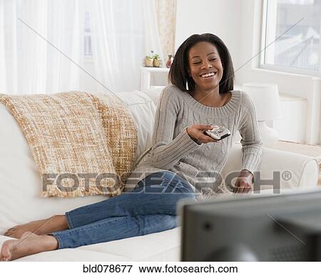 Mixed race woman watching television in living room View Large Photo Image Stock Photo - Mixed race woman watching television in living room. Fotosearch