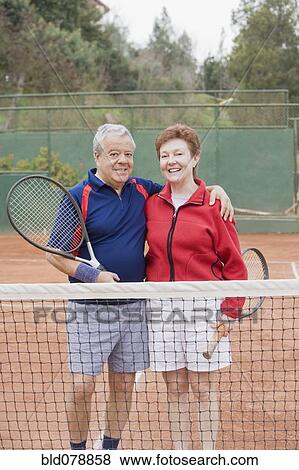 Stock Photo - Senior Hispanic couple playing tennis. Fotosearch