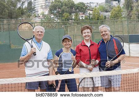 Stock Photo - Senior Hispanic couples playing tennis. Fotosearch