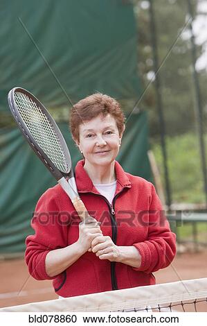 Stock Image - Senior Hispanic woman playing tennis. Fotosearch