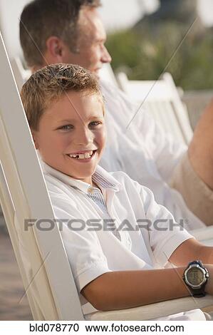 Stock Image - Smiling Caucasian boy sitting in chair. Fotosearch