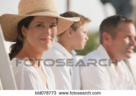 Stock Image - Smiling Caucasian woman sitting with family. Fotosearch