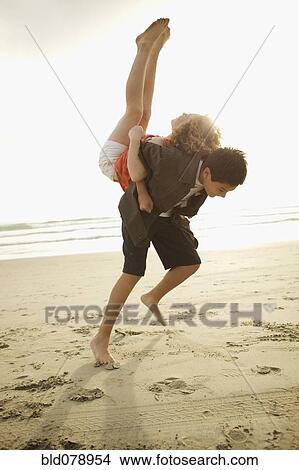 Boy lifting girl on back on beach View Large Photo Image Picture - Boy lifting girl on back on beach. Fotosearch