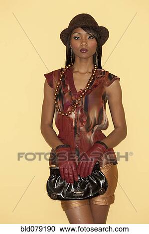 Stock Image - Glamorous mixed race woman holding purse. Fotosearch