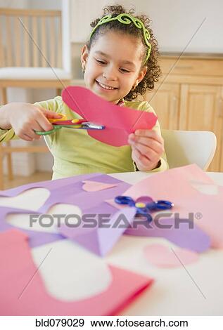 Stock Photo - Hispanic girl cutting construction paper. Fotosearch