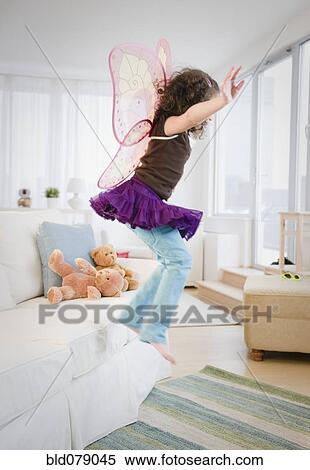Hispanic girl in fairy wings jumping off couch View Large Photo Image Stock Photography - Hispanic girl in fairy wings jumping off couch. Fotosearch