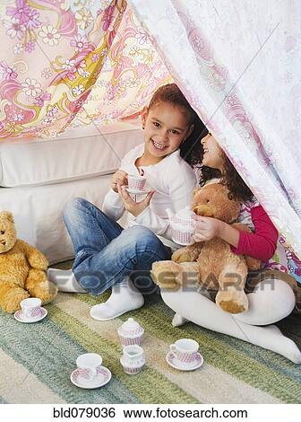 Stock Photograph - Hispanic sisters having tea party. Fotosearch