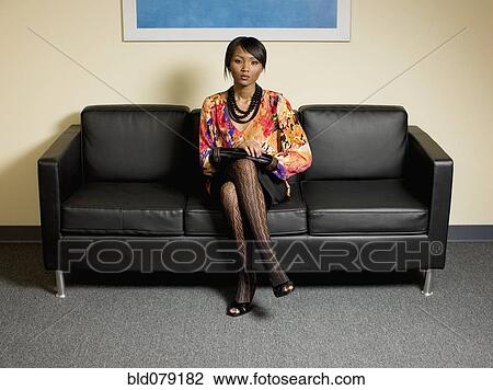 Stock Image - Mixed race businesswoman waiting in lobby. Fotosearch