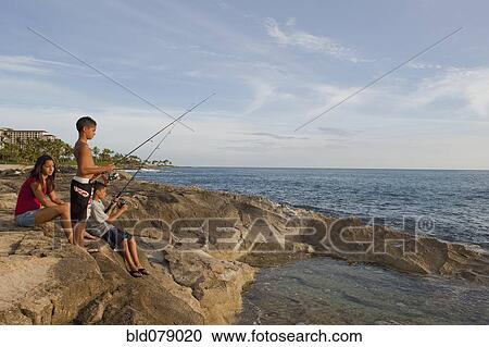 Stock Image - Mixed race children fishing in ocean. Fotosearch