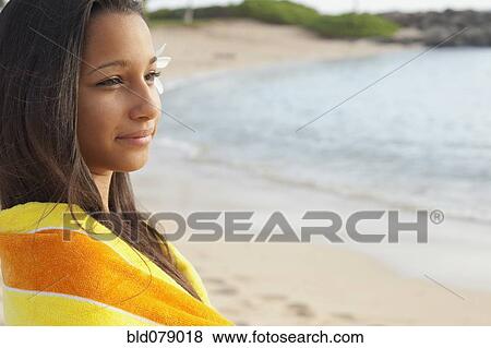 Stock Photo - Mixed race girl wrapped in towel on beach. Fotosearch